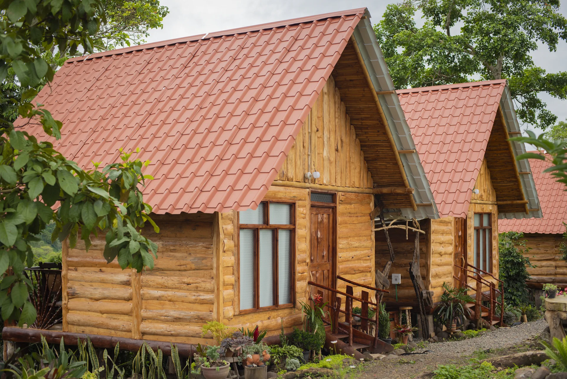 Cabañas de madera con techo terracota entre jardines y vegetación de la finca