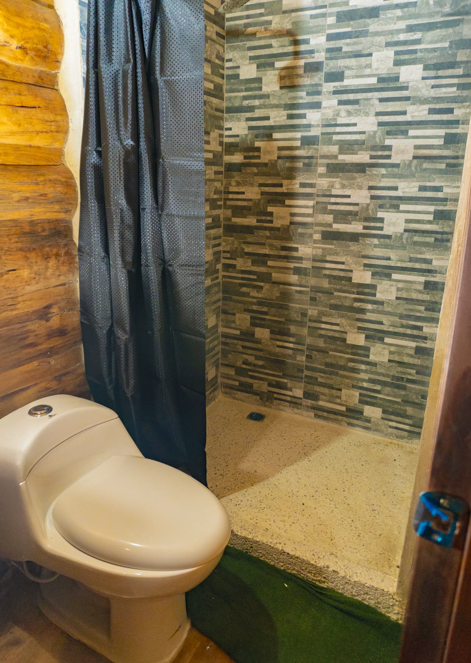 Baño de cabaña con ducha revestida y sanitario