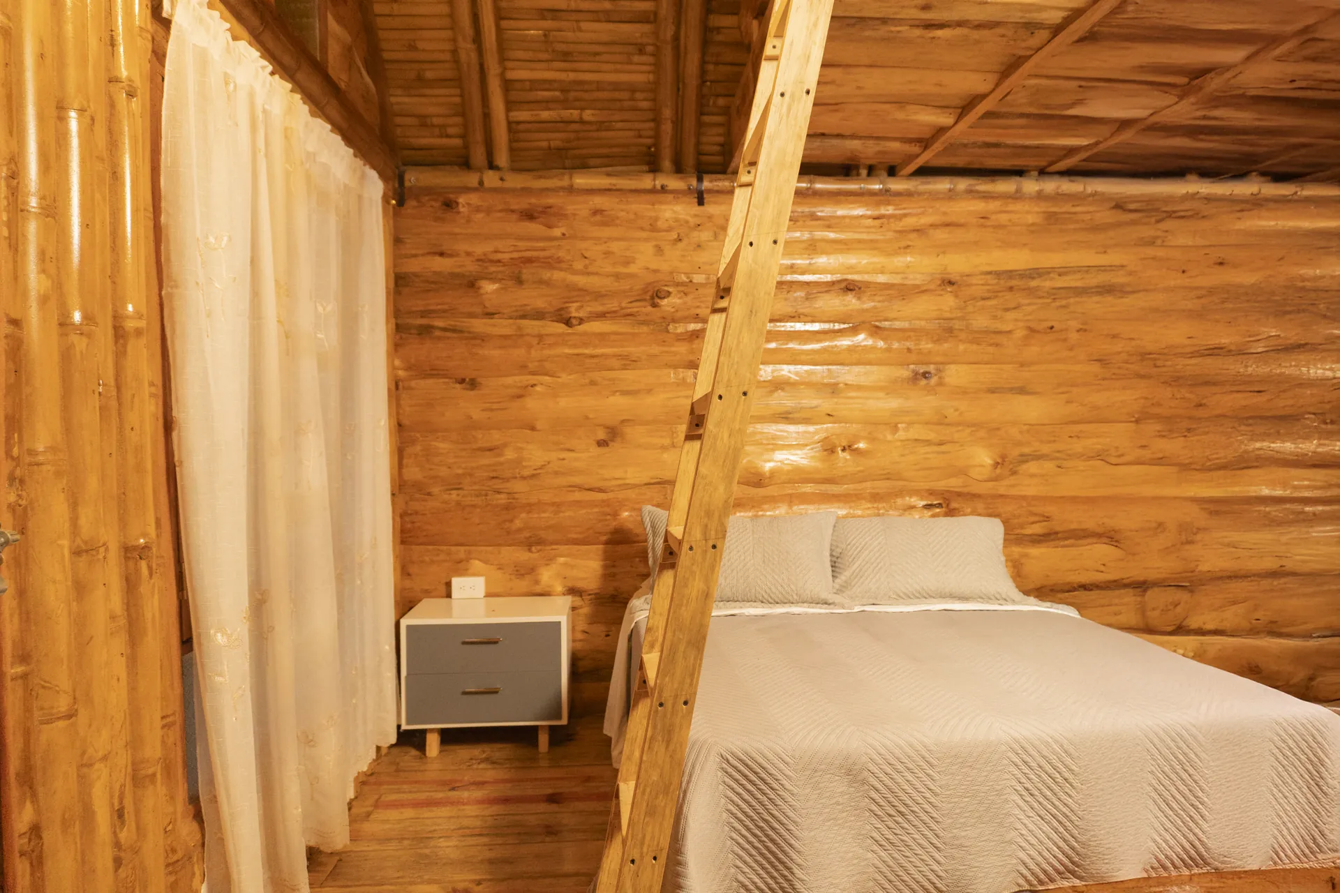 Habitación de cabaña de madera con cama, mesa de noche y ventana